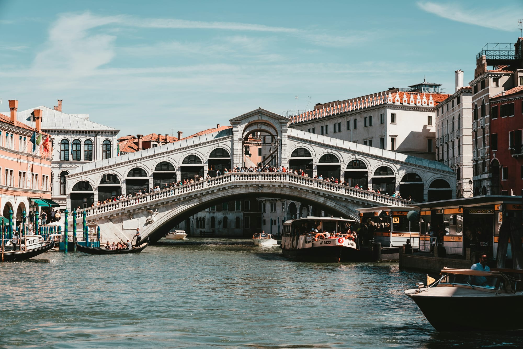 The iconic Rialto Bridge spanning the Grand Canal in Venice, with boats passing underneath.